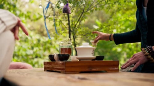 close-up The hands of a professional tea master who pours fresh natural green tea from a glass