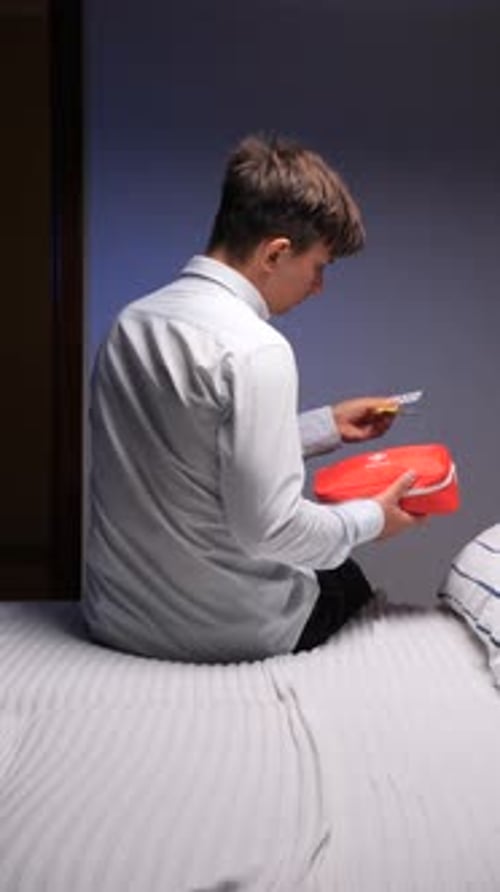 Man Examining Medication at Home on Bed