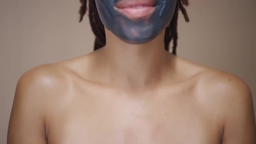 Young Woman Smiling with a Charcoal Face Mask