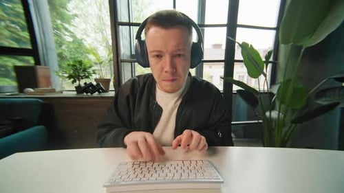 Man with Headphones Typing on Keyboard at Desk
