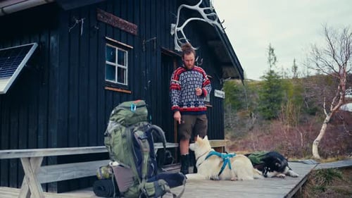 A Hiker Stands With His Two Dogs in Front of a Rustic Cabin Near Reinsjøen in Åfjord, Trøndelag, Nor