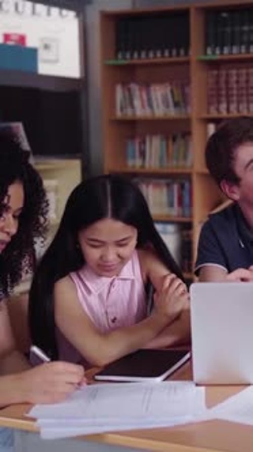 Group of Students at Library Gathering Together to Do a School Project As Teamwork Using a Laptop