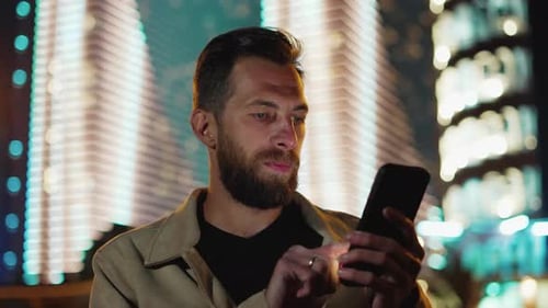 One Man Reads News Information on Phone at Dark Urban Street