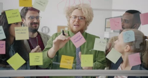 Diverse Business Team Brainstorming in Office Using Sticky Notes and Glass Board Taking
