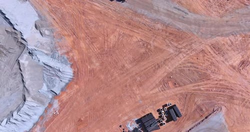 Construction Site with Heavy Machinery and Materials Spread Across a Large Area of Red Earth
