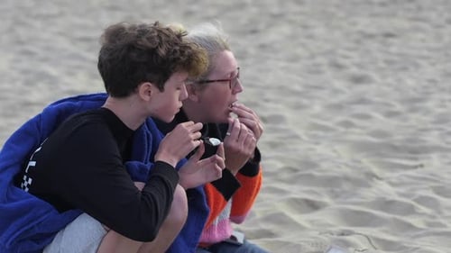 A Mother And Son Eating Toasted Chocolate Cookies On A White Sand Beach, A Perfect Bonding Time - Cl