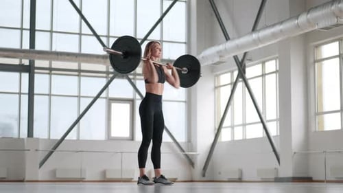 Woman Weightlifting Barbell in Bright Gym