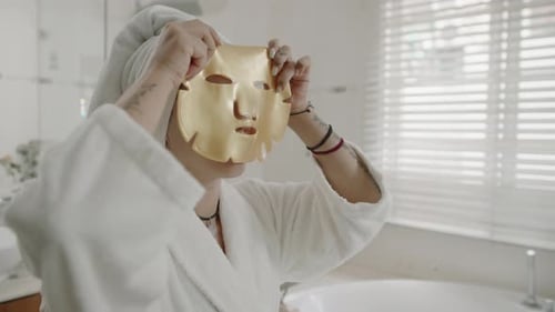 Caucasian Woman Applying Golden Sheet Mask on Face
