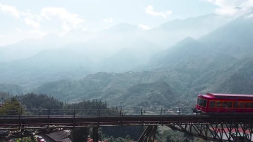 Un train rouge traverse un haut pont au-dessus de la pittoresque vallée de Hazy Mountain