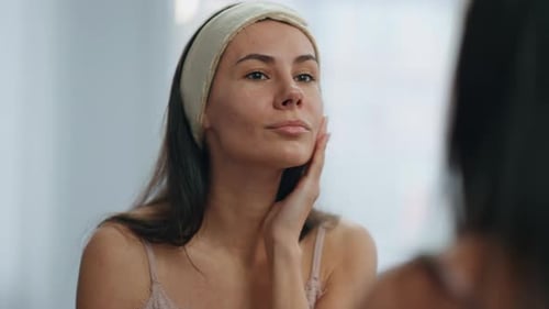 Woman Applying Lotion in Front of a Mirror