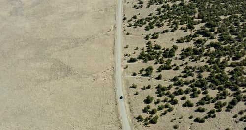 Car Driving Along Desert Road Toward Distant Mountains