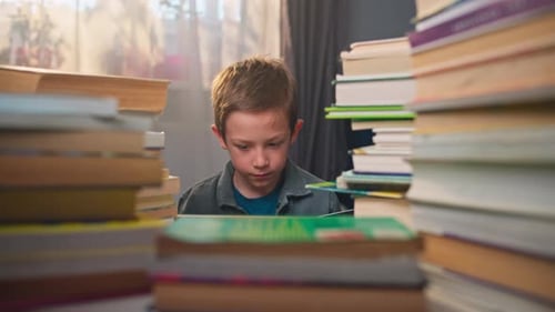 Boy Reads Book Surrounded by Piles of Books