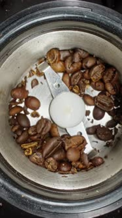 Rotierende Kaffeebohnen in einer Kaffeemühle Mahlen gerösteter Kaffeebohnen