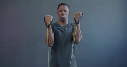 Slow Motion Portrait of Strong African American Man Training with Resistance Band Looking at Camera