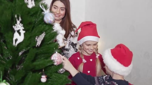 Die
süße Familie bereitet vor Neujahr einen Weihnachtsbaum in ihrem Haus vor. Junge Mutter und ihr 10-jähriges Kind