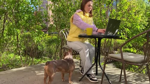 Woman Works on Laptop With Dog Outside