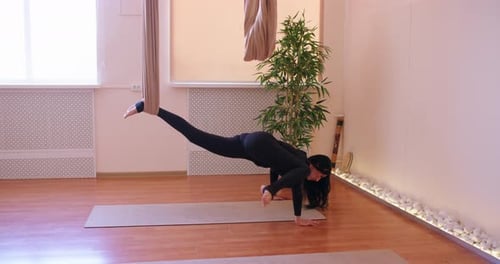 Woman Performs Aerial Yoga Pose With Instructor Indoors