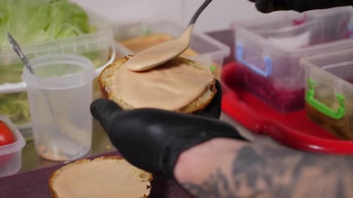 Chef Spreads Sauce on Toasted Bread Bun