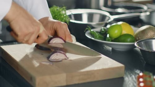 Close-up of a Chef Masterfully Cutting Colorful Vegetables and Onions on Cutting Board.