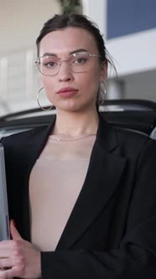 Une vendeuse de voitures professionnelle assiste les clients dans un showroom automobile moderne et lumineux