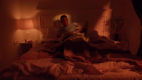 Insomnie Un homme à la peau foncée a perturbé son anxiété en essayant de se reposer au lit avec un téléphone