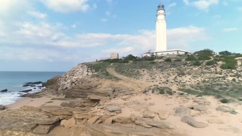 Aerial view flying forward past Trafalgar lighthouse in Los Canos de Meca Spain