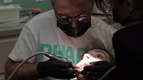 Two Doctors a Man and a Woman in Protective Masks in a Dental Clinic Serve a Patient The Work of an