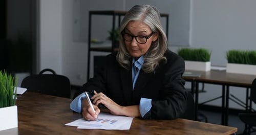 Mature Woman Working at Desk Analyzing Data