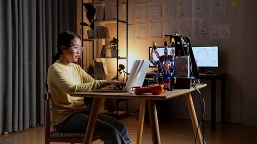 Teen Asian Girl Working About A Cyborg Hand On A Laptop At Home