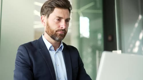 Busy businessman works on a laptop while sitting at workplace in business office. Entrepreneur