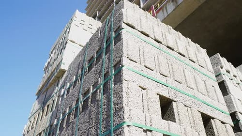 Großer Stapel von Bimssteinblöcken und Blöcken, die in Würfelform auf Paletten verpackt sind.