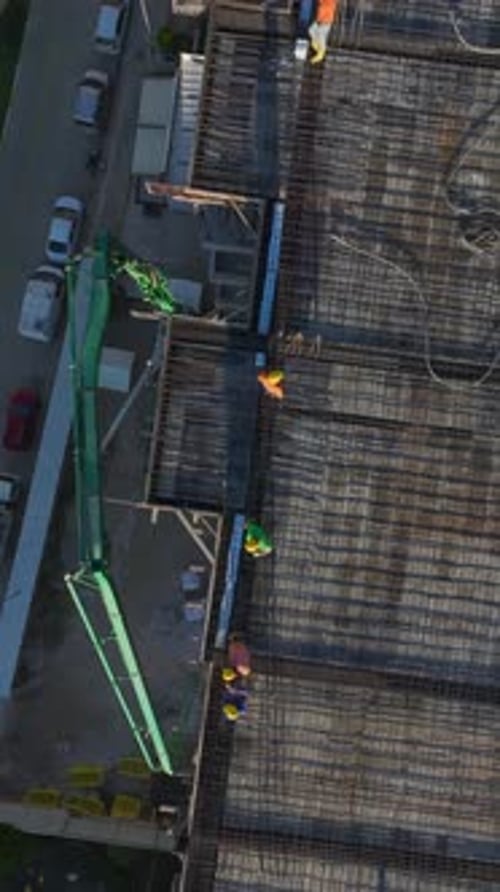 Vertical Video of Workers Laying Concrete Foundations and a Crane Assisting With Material Transport