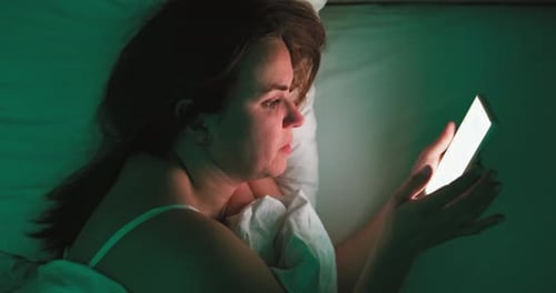 Woman Using Smartphone in Bed at Night