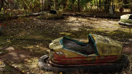 Broken and overgrown bump cars in Pripyat amusement park, pan right view