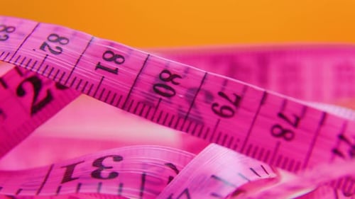 Close Up of a Pink and Yellow Measure Tape on Colored