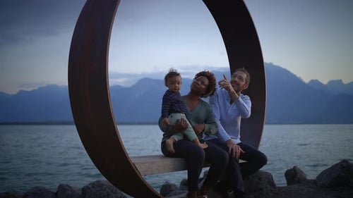 Captivating Family Portrait Captured By the Tranquil Water with a Beautiful Mountain Background