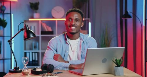 Man at Desk with Laptop Smiling to Camera