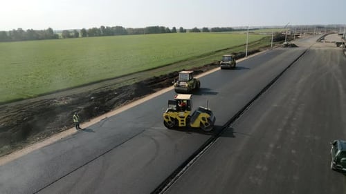 Road Rollers Compacting Fresh Asphalt on a New Road Clip