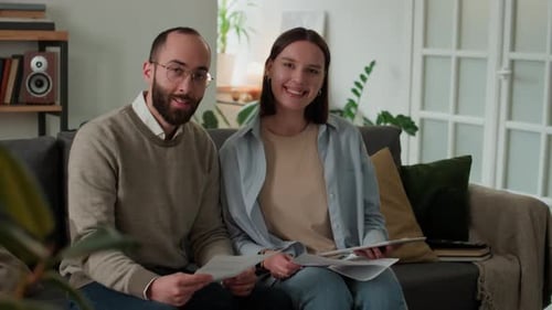 Couple Reviewing Papers Together on Couch at Home