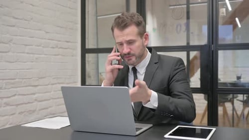 Man Working and Talking on Phone in Office