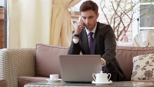 Young Adult Using Laptop and Cellphone in Cafe
