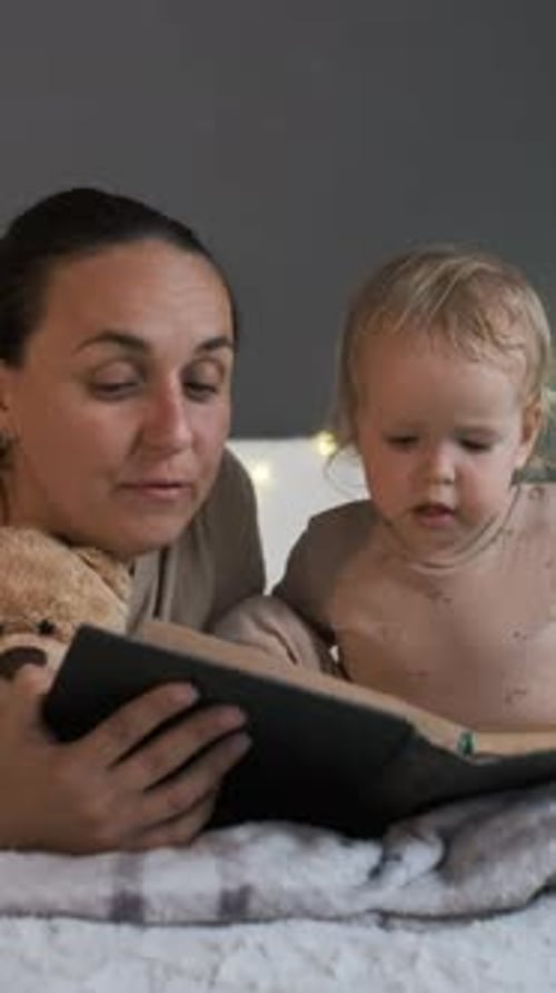 Mother and Child Read a Book on Blanket