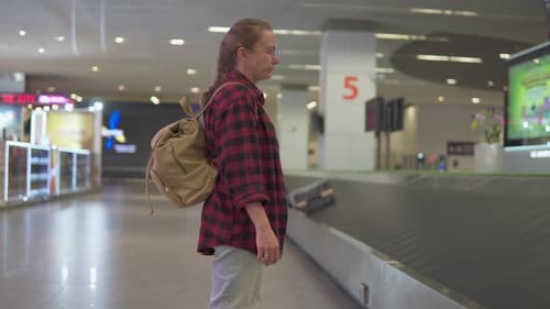 Female tourist with backpack is waiting her luggage in airport