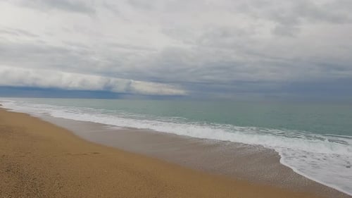 Coarse sand beach sea wave in slow motion at 120fps 4k cloudy day turquoise water single sea waves B