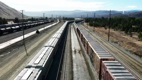 forward flight dolly drone shot flying between cargo trains on a railroad station in a desert enviro