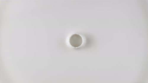 Goutte de lait frais tombant et éclaboussant dans une mare laiteuse vue d'en haut. Ralentissement et surface ondulée