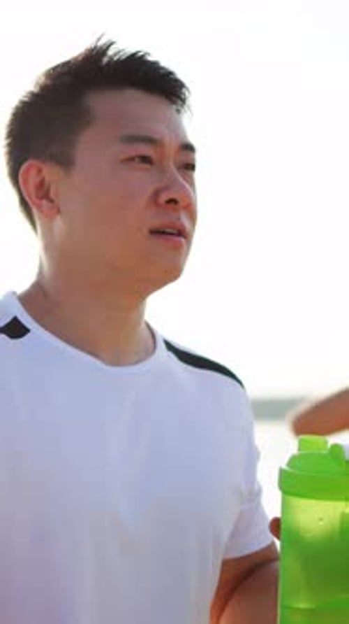 Adult Man Wipes Sweat near Beach Holding Water Bottle