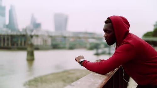 A Black Man Runner With Earphones And Hood On His Head In A City. Copy Space.