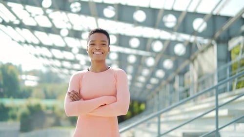 Portrait smiling pretty African American woman athlete standing urban background city stadium look