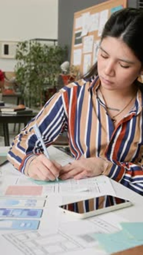 Young Woman Designs Mobile App Interfaces at Her Desk